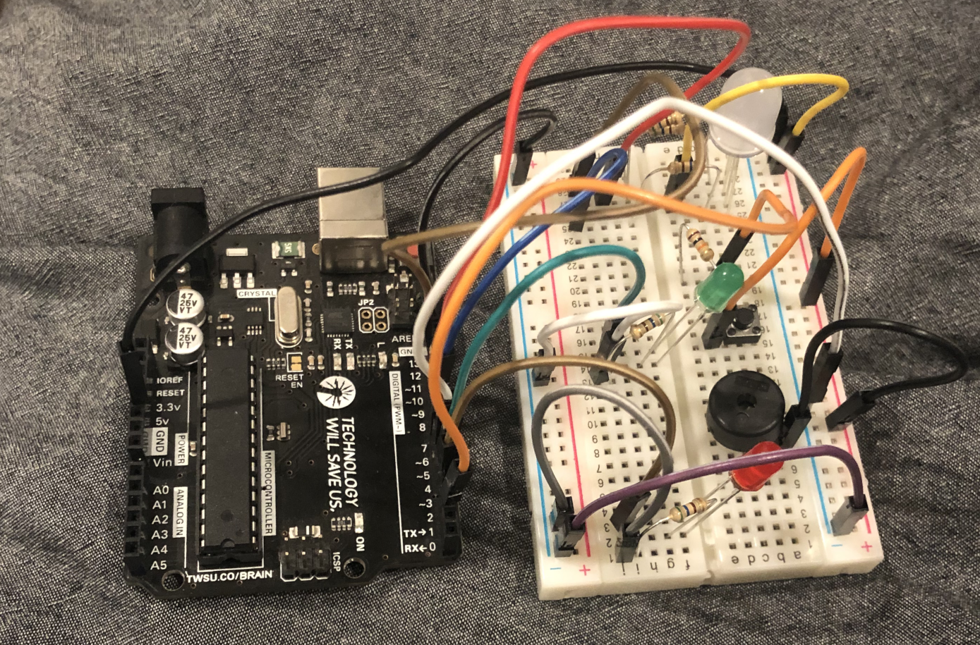 a picture of a breadboard with red, green, and RGB LEDs, as well as a Piezo buzzer attached to an Arduino Uno