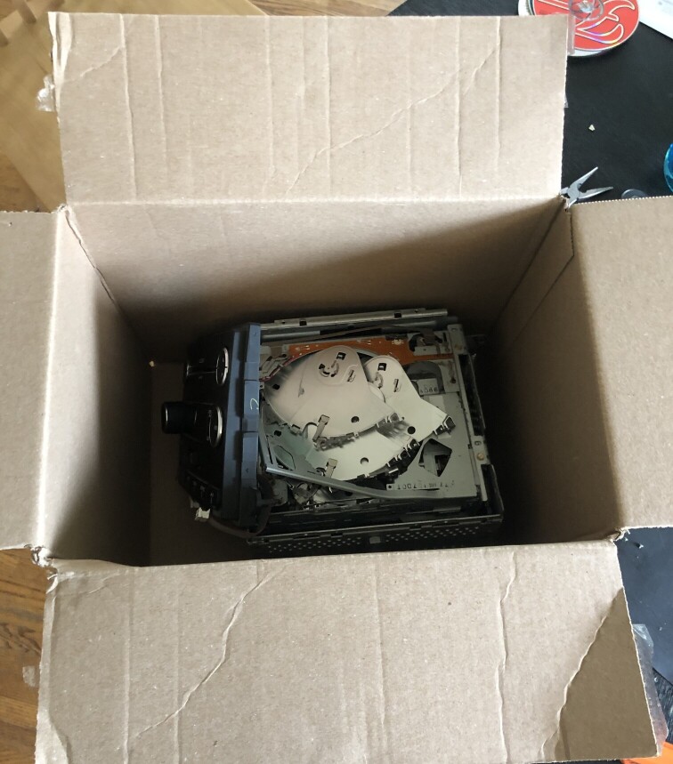 a cardboard box full of broken CD reader parts