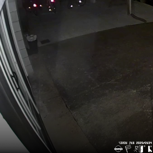 a square image of a security camera picture. overlaying this picture is some text in a blocky, arcane language, and some company logos in the bottom right corner. These company logos consist of one which looks like a human with their eyes redacted by a rectangle, a flag with three vertical stripes, a bipedal organism with antlers running through a door (similar to the exit sign person), and a glyph which looks like a lambda.